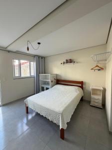 a bedroom with a bed in a white room at Espaço inteiro e tranquilo in São José