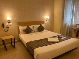 a hotel room with a bed with a phone on it at Crayons Hotel in Chennai