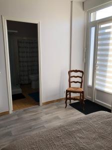 a bedroom with a chair and a door to a bathroom at Le Logis du GAST Chambre Taupe in Le Gast