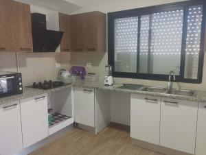 a kitchen with white cabinets and a sink and a window at Nozeht el soltan in Potinville