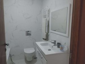 a white bathroom with a toilet and a sink at Nozeht el soltan in Potinville
