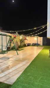 a wooden deck with lights and grass at night at فيلا وشاليه وارفة in Medina