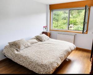 a bed in a bedroom with a large window at CASA Arce in Boqueijón