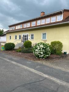 una casa gialla con fiori bianchi davanti di Ferienwohnung Waldblick a Scheidt