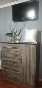 a wooden dresser with a television on top of it at Radiant Residence in Grahamstown