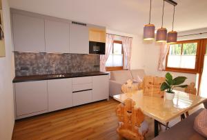 a kitchen with white cabinets and a table in a room at Residenz Erschbaum in Valdaora