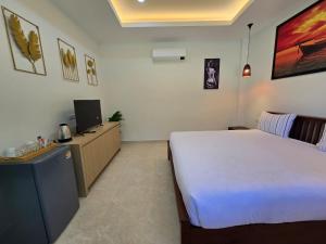 a bedroom with a bed and a desk with a television at Palm Garden Villa Aonang in Ao Nam Mao