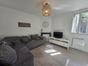 a living room with a couch and a tv at 2 Pause détente avec terrasse privée in Ernée