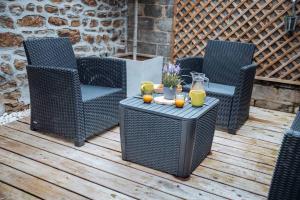 three wicker chairs and a table with drinks on a deck at 2 Pause détente avec terrasse privée in Ernée