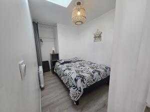 a bedroom with a bed and a chandelier at 2 Pause détente avec terrasse privée in Ernée