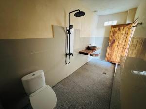a bathroom with a toilet in a room with a door at Nona Lodge in Tetebatu +101 photos