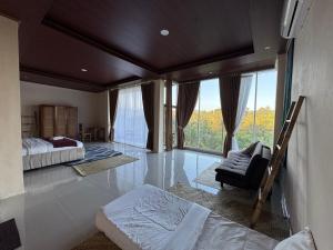 a bedroom with a bed and a chair and windows at Nona Lodge in Tetebatu