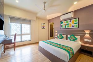 a bedroom with a bed and a desk and a window at Treebo Premium Lavender Kochi Infopark in Cochin +32 photos