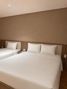two large white beds in a room at Thanh Bình Hotel - Buôn Ma Thuột in Buon Ma Thuot