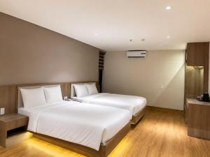 a hotel room with two beds and a television at Thanh Bình Hotel - Buôn Ma Thuột in Buon Ma Thuot