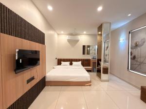 a bedroom with a bed and a flat screen tv at Hotel Shree Maya Comfort Inn in Ujjain