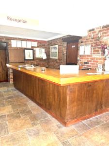 a reception counter in a room with a brick wall at The Rivenhall Hotel in Rivenhall