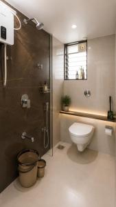 a bathroom with a toilet and a shower with a glass door at Neelaashray Sea view apartment in Ratnagiri +8 photos