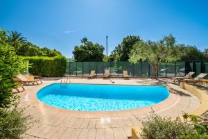 a swimming pool in a yard with chairs around it at Résidence Pierre & Vacances La Rostagne in Juan-les-Pins