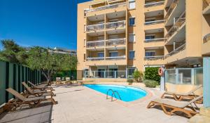an outdoor swimming pool with lounge chairs and a building at Résidence Pierre & Vacances La Rostagne in Juan-les-Pins