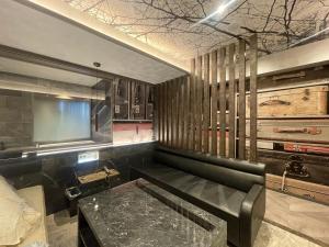 eine Bar mit einer schwarzen Ledercouch und einem Tisch in der Unterkunft HOTEL the CACTUS in Kasugai