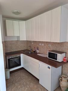 a kitchen with white cabinets and a microwave at Stan Foča in Foča +4 photos
