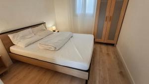 a bed with white sheets and pillows in a room at A Casa Radica, appartement rez-de-villa au calme, jardin et maquis in Eccica-Suarella