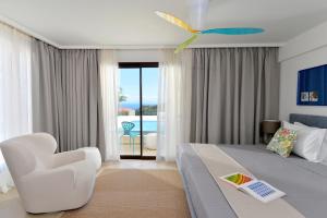 a hotel room with a bed and a white chair at Althea Resort in Áno Loutrón +45 photos