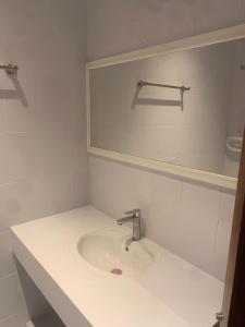 a white bathroom with a sink and a mirror at Hotel room in Salalah