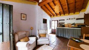 a living room with two chairs and a kitchen at Cortijo Lagar de Luisa in Borge