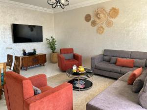 a living room with a couch and chairs and a tv at Beach apartment down town in Agadir