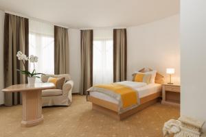 a bedroom with a bed and a chair and a table at Leonardo Med Spa Resort in Nondorf +23 photos