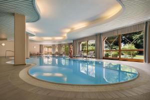 a pool in a hotel lobby with a large swimming pool at Leonardo Med Spa Resort in Nondorf