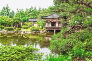 a garden with a house next to a pond at Tanakaya in Kurobe