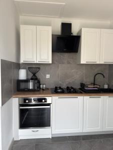 a kitchen with white cabinets and a stove at Apartament nad jeziorem in Lubkowo