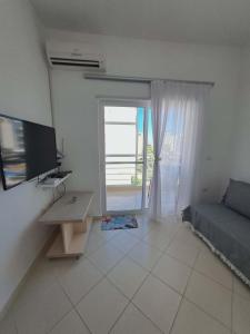 a living room with a couch and a television and a window at Mimosa Apartment in Vlorë