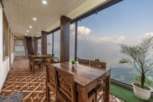 a dining room with a table and a large window at The Fagu Valley Retreat l Rooms and Restaurant l Family Groups & Events l Open Air Lawn l Kufri by Exotic Stays in Shimla +12 photos