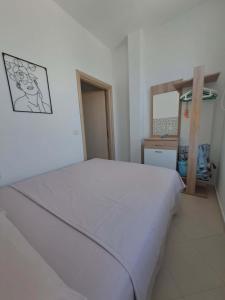 a bedroom with a white bed in a room at Mimosa Apartment in Vlorë