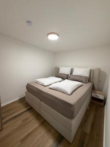 a bed in a room with white walls and wood floors at Bartenwetzer Schleusenhaus 1 in Melsungen