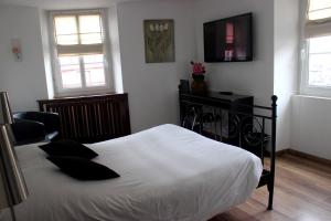 バールにあるア ラ メゾン ルージュ オテル ＆ レストランのベッドルーム1室(白いシーツと黒い枕のベッド1台付)