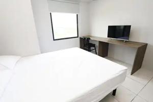 a white room with a desk and a bed and a computer at Reverdale in Bekasi
