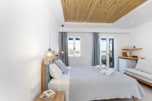 a white bedroom with a bed and a couch at Alykes Studios & Suites in Agios Prokopios
