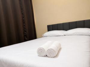two rolled towels sitting on a white bed at Hotel Confort in Quixadá