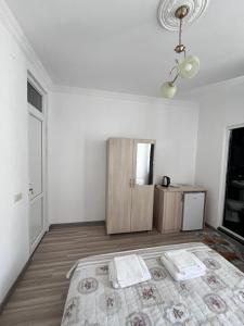 a white room with a bed and a cabinet at Zuri Kvariati in Kvariati