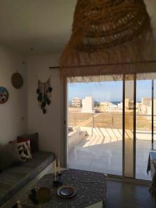 a living room with a couch and a large window at Kelibia ezzahra 2min a pied du plage in Ḩammām al Ghazzāz +4 photos