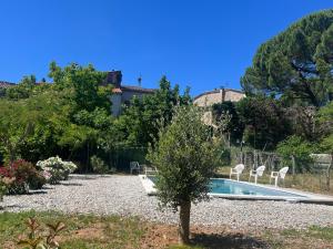 a garden with a swimming pool and two chairs at Gîte des Lauriers Blancs in Laurac-en-Vivarais