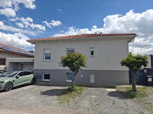 a white building with a car parked in a parking lot at Antonio Appartement in Steinabrückl