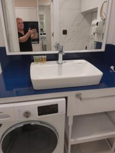 a woman taking a picture of a washing machine in a bathroom at ა ბლოკი in Stantsiya Batumi-Passazhirskaya