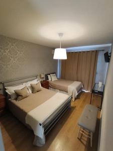 a hotel room with two beds and a chair at Residencial Do Rita em Rio Caldo in Geres