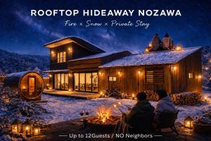 a group of people sitting in front of a house in the snow at 雪灯庵 in Iiyama +6 photos